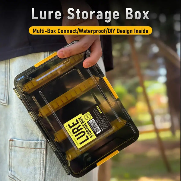 Hand holding translucent amber lure storage box with yellow frame and latch