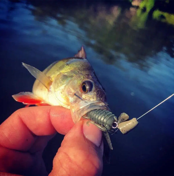 Light gray soft fishing lure with orange accents, glitter body, and treble hook