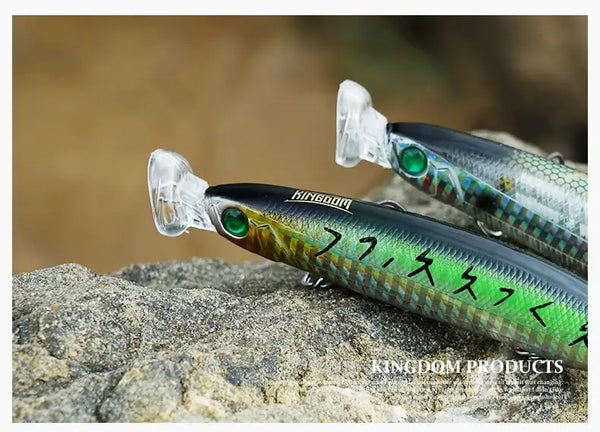 Two floating minnow lures with glass eyes and treble hooks on rocks