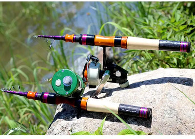 Telescopic fishing rod on rocks beside greenery with spinning reel attached