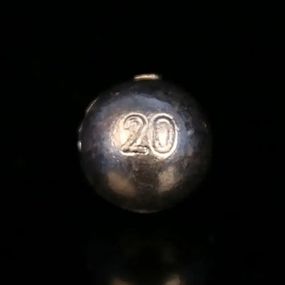 Dark gray lead ball sinker with embossed marking and small top hole
