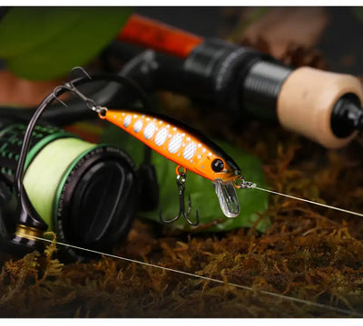 Sinking minnow fishing lure in bright orange with white spots and treble hooks