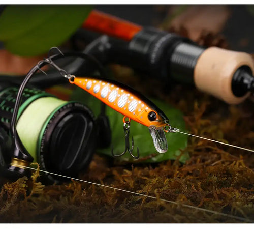 Sinking minnow fishing lure in bright orange with white spots and treble hooks