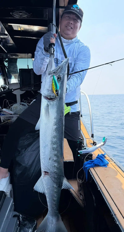 NOEBY lure with attached fish catch on fishing line held by an angler on a boat