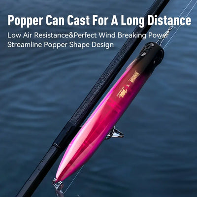 Floating popper fishing lure, magenta-pink and silver body, red front cup, angled on a fishing rod