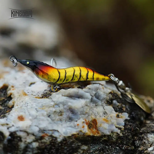 Yellow and orange metal spinner shrimp fishing lure with spoon blade and treble hook