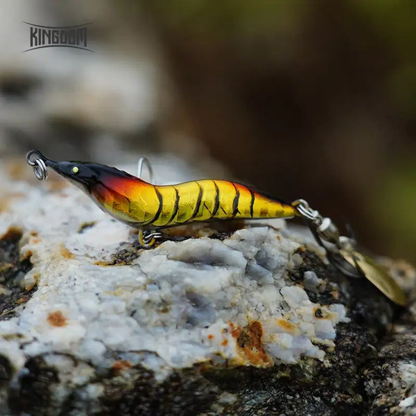 Yellow and orange metal spinner shrimp fishing lure with spoon blade and treble hook
