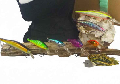 Assorted hard-body fishing lures in green, yellow, purple and gold on driftwood