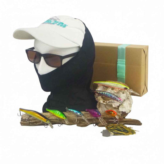 Cardboard box with assorted colorful hard-body fishing lures arranged on driftwood