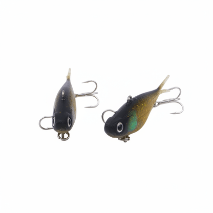 Soft plastic fishing lures, two dark bodies with gold-green shimmer and treble hooks
